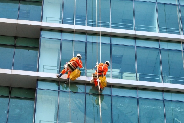 two men doing window cleaning of a building using rope access method