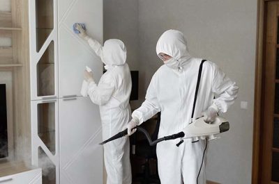 two janitor in white disposable coverall and mask doing deep cleaning and sanitization of a home